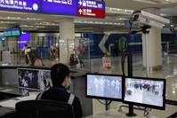 A health surveillance officer monitors passengers arriving at the Hong Kong International airport, Hong Kong, Jan. 4, 2020. (AP Photo)