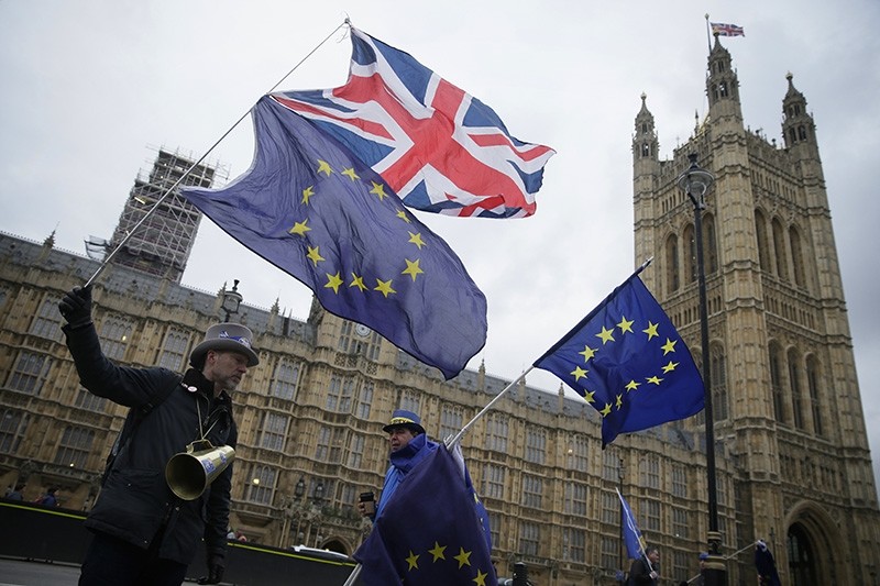Demonstrators opposing Brexit wave flags as The European Commission's Chief Negotiator for the UK exiting the European Union, Michel Barnier is at 10 Downing Street for a meeting, outside the Houses of Parliament, London, Feb. 5, 2018. (AP Photo)