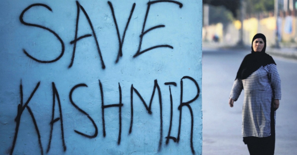 A Kashmiri woman stands next to graffiti written on a wall in Srinagar, Kashmir, Sept. 15, 2019.