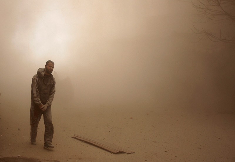 A man walks in the dust following Assad regime airstrikes on the opposition-held besieged town of Douma in the eastern Ghouta region, on the outskirts of the capital Damascus, Syria, Feb. 7, 2018. (AFP Photo)