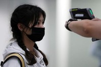 A passenger gets her temperature checked by a worker using an infrared thermometer amid coronavirus outbreak, at Hong Kong International Airport, Feb. 7, 2020. (Reuters Photo)