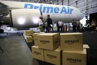 Amazon.com boxes are stacked near a Boeing 767 Amazon Prime Air cargo plane on display in a Boeing hangar.