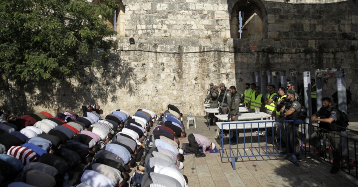 Israeli border police stand guard as Muslim men pray outside the Al-Aqsa Mosque compound, Jerusalem, July 16, 2019.