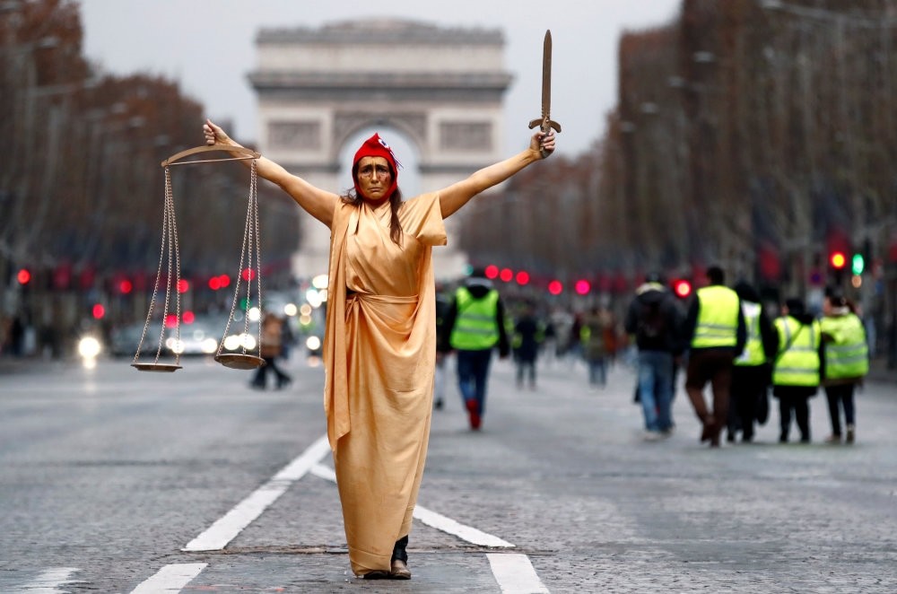 A woman dressed as ,Marianne,, a French symbol of justice, poses during a demonstration by the ,yellow vests, movement at the Champs Elysees near the Arc de Triomphe, Paris, Dec. 22.