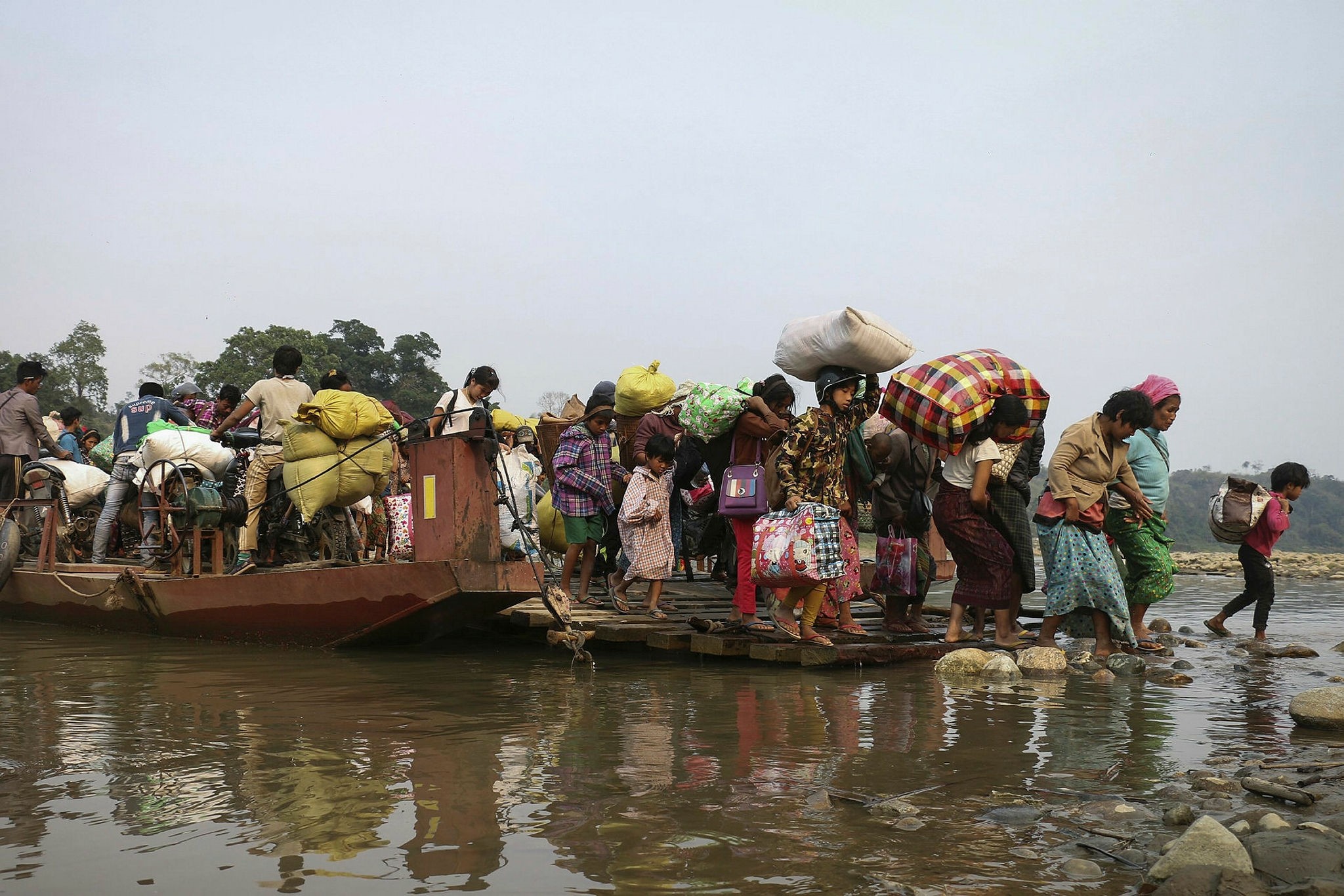Displaced Kachin residents cross the Malikha river on a ferry to escape Myanmar army atrocities, April 26.