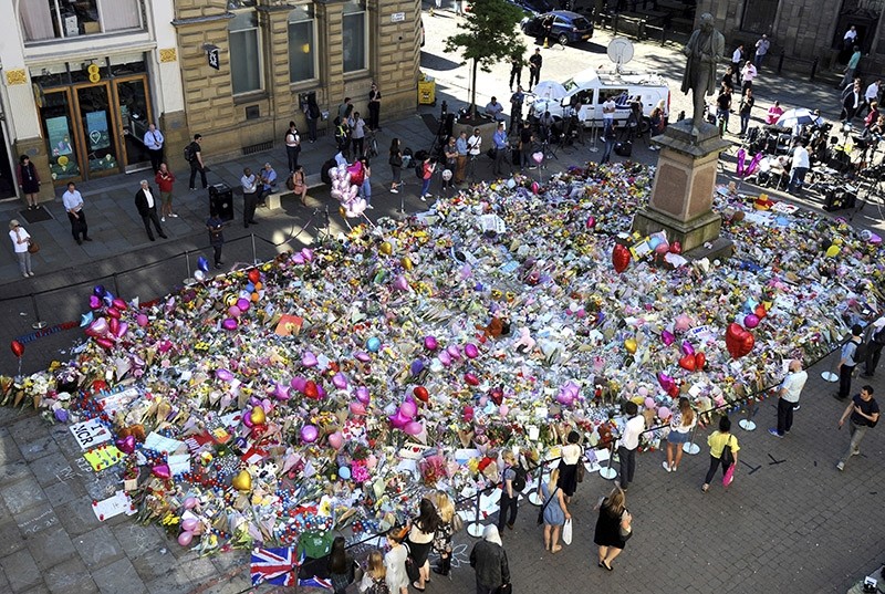 People stand around flower tributes for the victims of Monday's bombing at St Ann's Square in central Manchester, Britain, Friday, May 26 2017. (AP Photo)