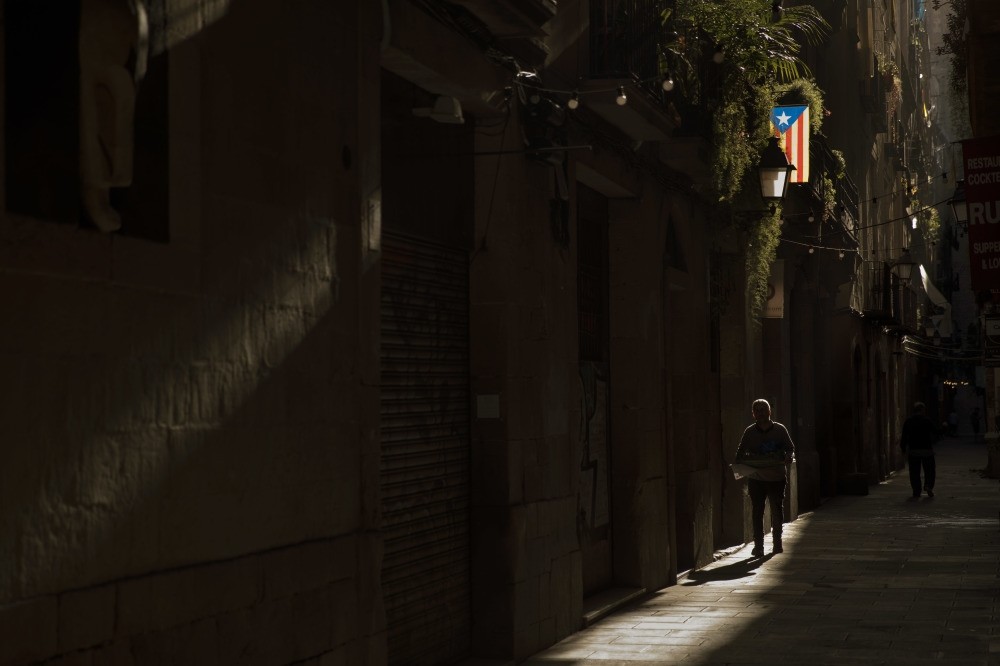 A man walks past a Catalan flag hanging off a balcony in downtown Barcelona, Oct. 24. 