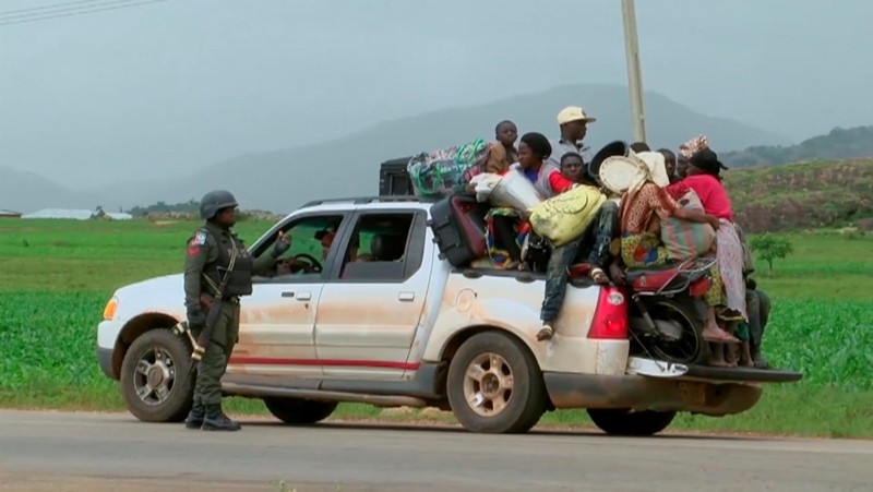 Security personal at a check point observe a pickup truck loaded with people and their belongings as they drive off to safety as police attempt to restore calm, in the town of Jos, Nigeria, Sunday June 25, 2018. (Nigeria Government via AP)