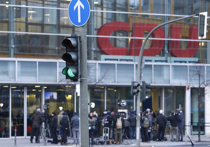 A traffic light shows green when journalists wait outside the CDU headquarters during the coalition talks on forming a new German government between Angela Merkel's CDU and the Social Democratic Party in Berlin, Germany, Feb. 7, 2018. (AP Photo)