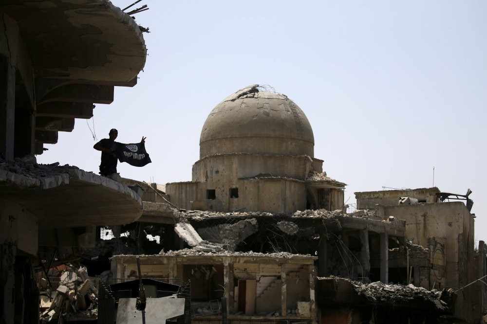 A member of Iraqi security forces holds a Daesh flag on the top of a building destroyed in clashes in the old city of Mosul, Iraq July 10. 