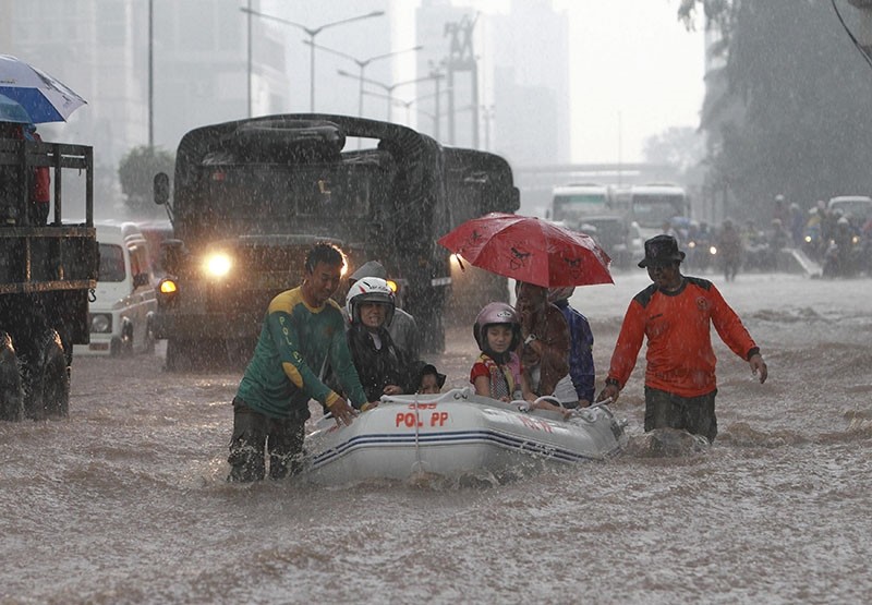 People sit on an inflatable raft as they move through a flooded street to try to reach higher ground, in the business district in Jakarta January 18, 2013. (Reuters Photo)