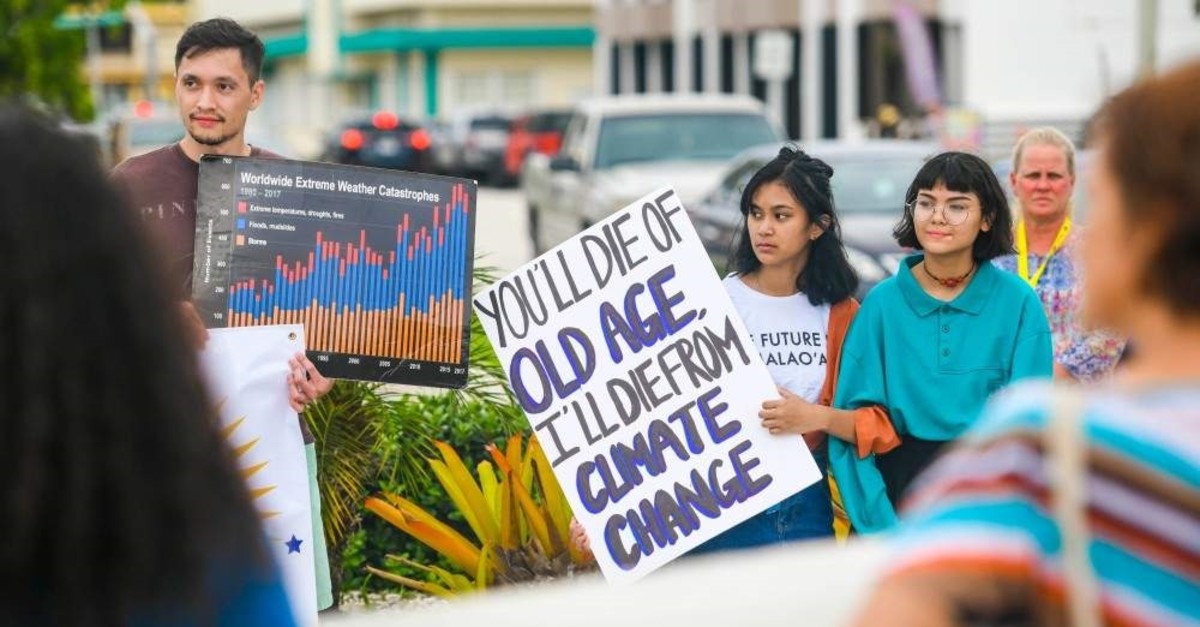 Supporters carry signs during a rally, hosted by the Micronesia Climate Change Alliance, to raise awareness of issues affect global climate change, in front of the Guam Congress Building in Hag  t  a on Wednesday, Aug. 7, 2019. (Reuters Photo)