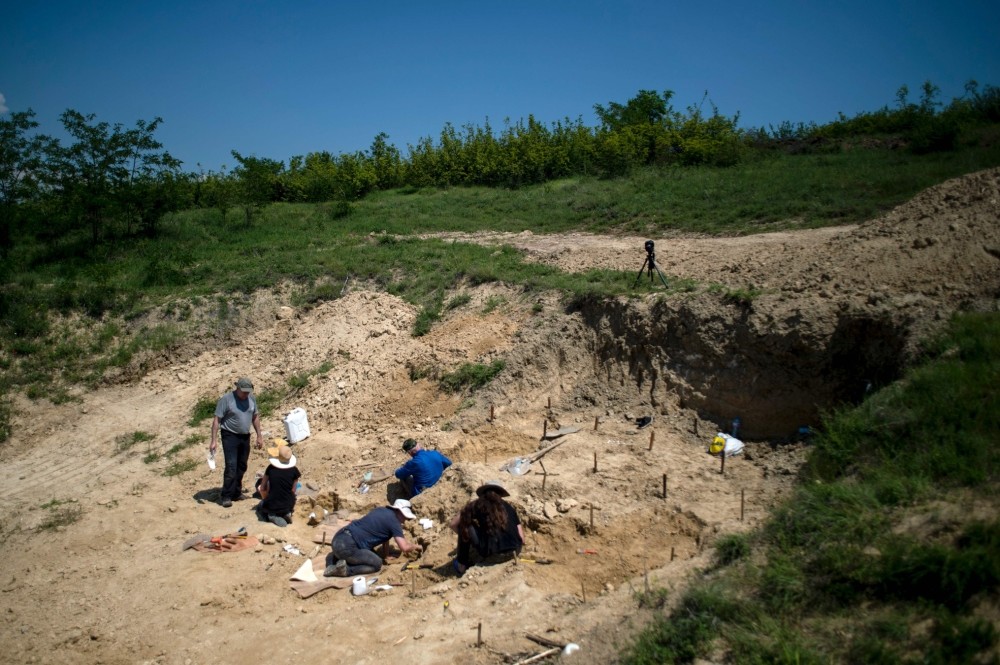 Paleontologists work near the site where a fossilised tooth with three roots was found in 2002, near the village of Rupkite.