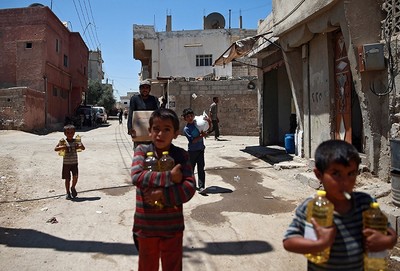 Syrian children and a man are seen carrying food aid in Douma, near Damascus, Syria August 6, 2017 (Reuters Photo)