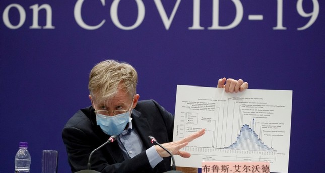 بروس أيلوارد من منظمة الصحة العالمية يحمل مخططًا في مؤتمر صحفي قدمته البعثة المشتركة بين منظمة الصحة العالمية والصين حول تفشي فيروس كورونا في بكين العام الماضي رويترز