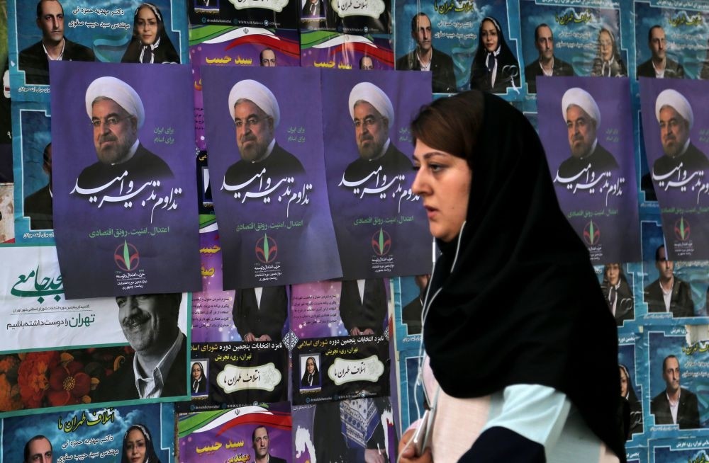An Iranian woman walks past a wall plastered with election posters of Iranian President and candidate in the upcoming elections, Hassan Rouhani, in capital Tehran on May 18, 2017.