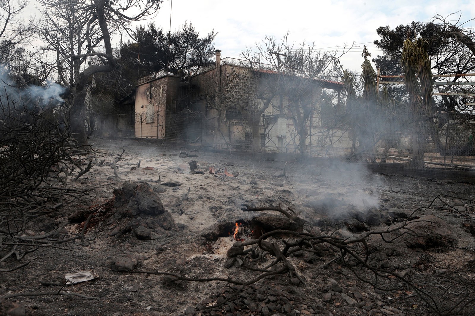 A view of smoldering fire and a burnt house (background) in Argyra Akti, Mati, close to Nea Makri, in Attica, Greece, July 24, 2018.