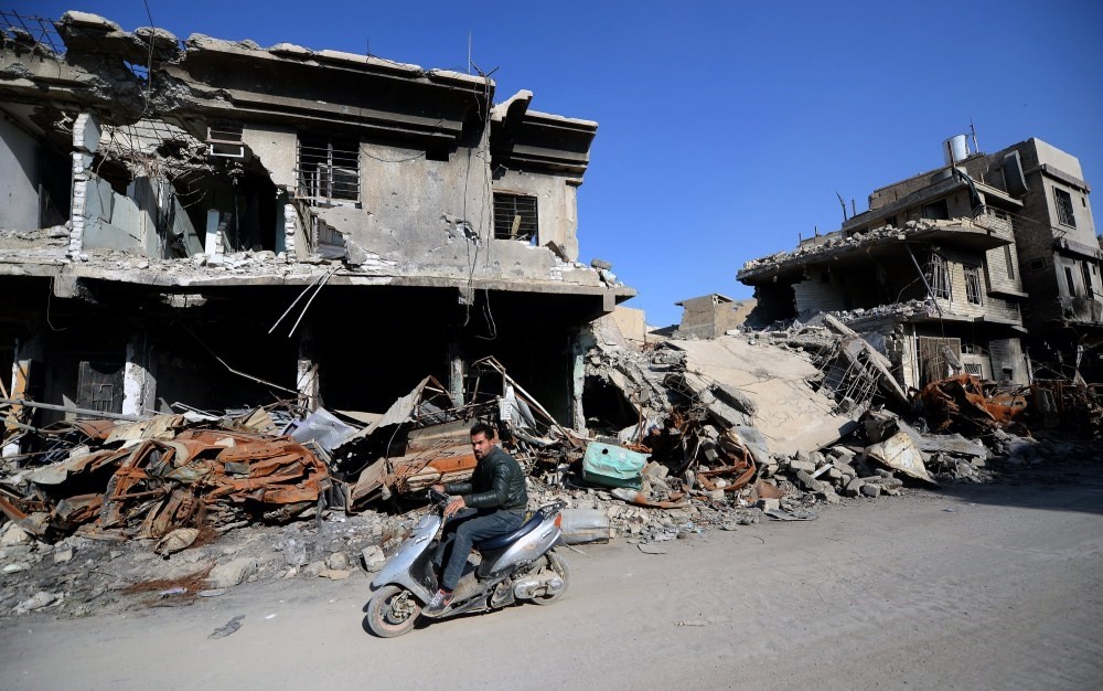 A man rides a scooter near destroyed buildings at the old city area in western Mosul months after the province of Nineveh was recaptured from Daesh militants.