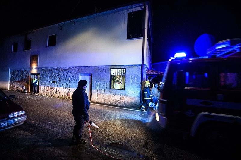 Policemen and firefighters work outside the building, in the background, where a heater exploded killing people in the village of Vila Nova da Rainha, outside Tondela, northern Portugal, in the early hours of Sunday, Jan. 14 2018. (AP Photo)