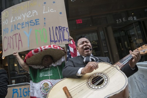 A demonstrator dances and sings along the Mariachi Tapatio de Alvaro Paulino band as they perform during a demonstration across the street from the building that once housed the office space of Aaron Schlossberg, May 18, 2018, in New York. (AP Photo)