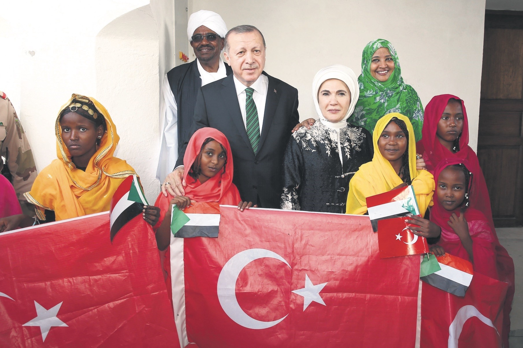 President Erdou011fan (C), accompanied by first lady Emine Erdou011fan, pose for a photograph with Sudan's President Omar al-Bashir and first lady Widad Babiker u00d6mer Modawi alongside local people holding the Sudanese and Turkish flags in Port Sudan, Dec. 25.