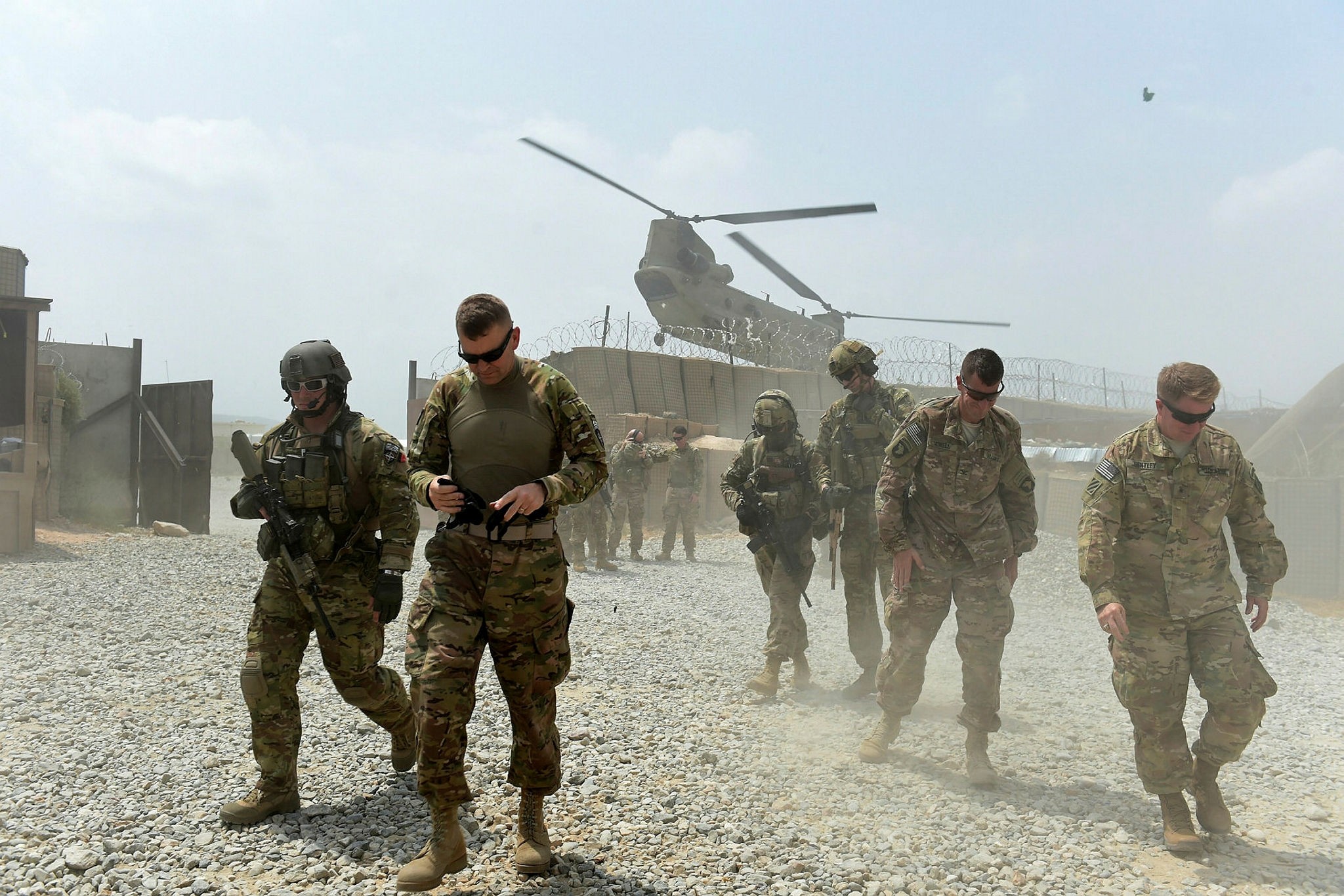U.S. army soldiers walk as a NATO helicopter flies overhead in the Khogyani district in the eastern province of Nangarhar, Afghanistan.