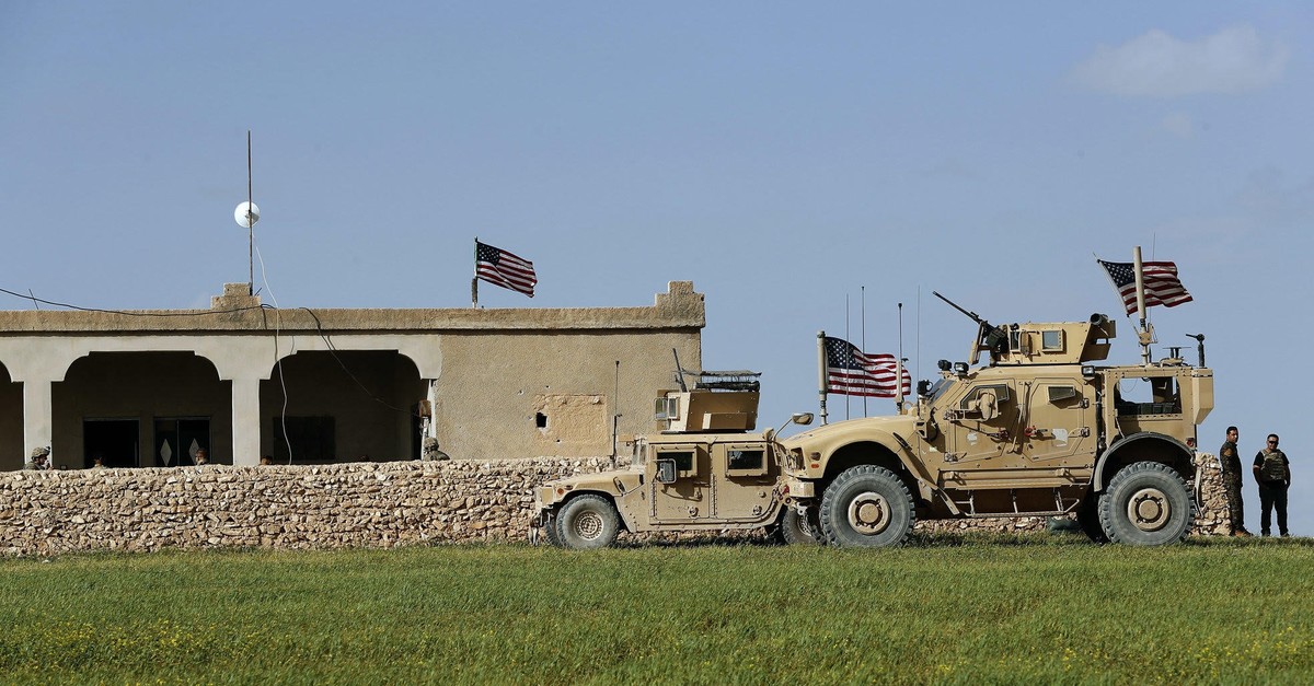 U.S. soldiers sit in front of a house that has been turned into an outpost on a road leading to the tense frontline between U.S.-backed YPG terrorists and Turkish-backed fighters in Manbij, March 29, 2018.