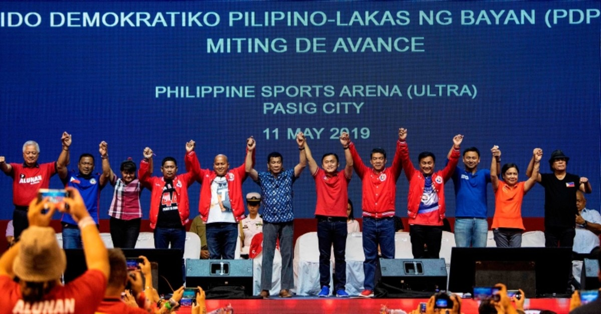 Philippine President Rodrigo Duterte (C) raises the hands of senatorial candidates during the Partido Demokratiko Pilipino-Lakas Bayan (PDP-LABAN) in Manila on May 11, 2019 ahead of the mid-term elections on May 13. (AFP Photo)