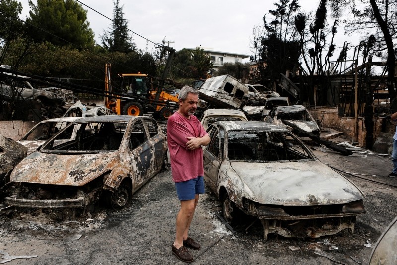 A man pauses as he stands amidst burned cars following a forest fire in Mati a northeast suburb of Athens, Greece, 24 July 2018. (EPA Photo)