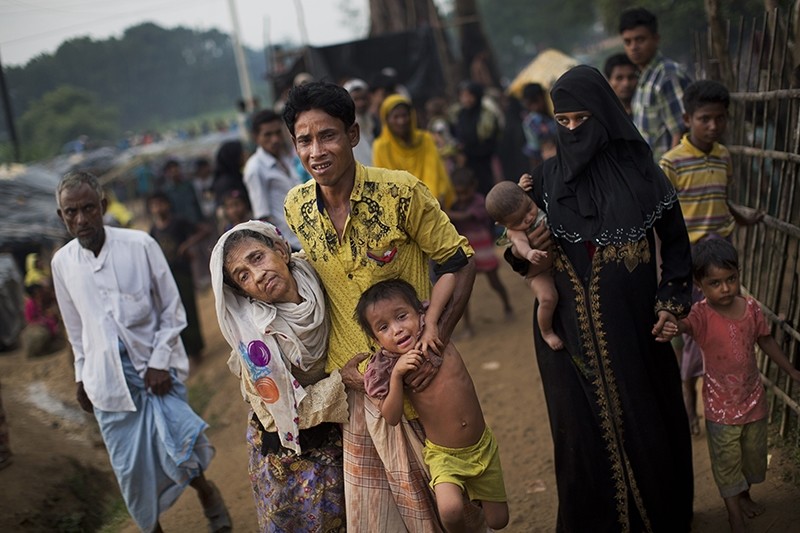  In this file photo, an exhausted Rohingya helps an elderly family member and a child as they arrive at Kutupalong refugee camp after crossing from Myanmmar (AP Photo)