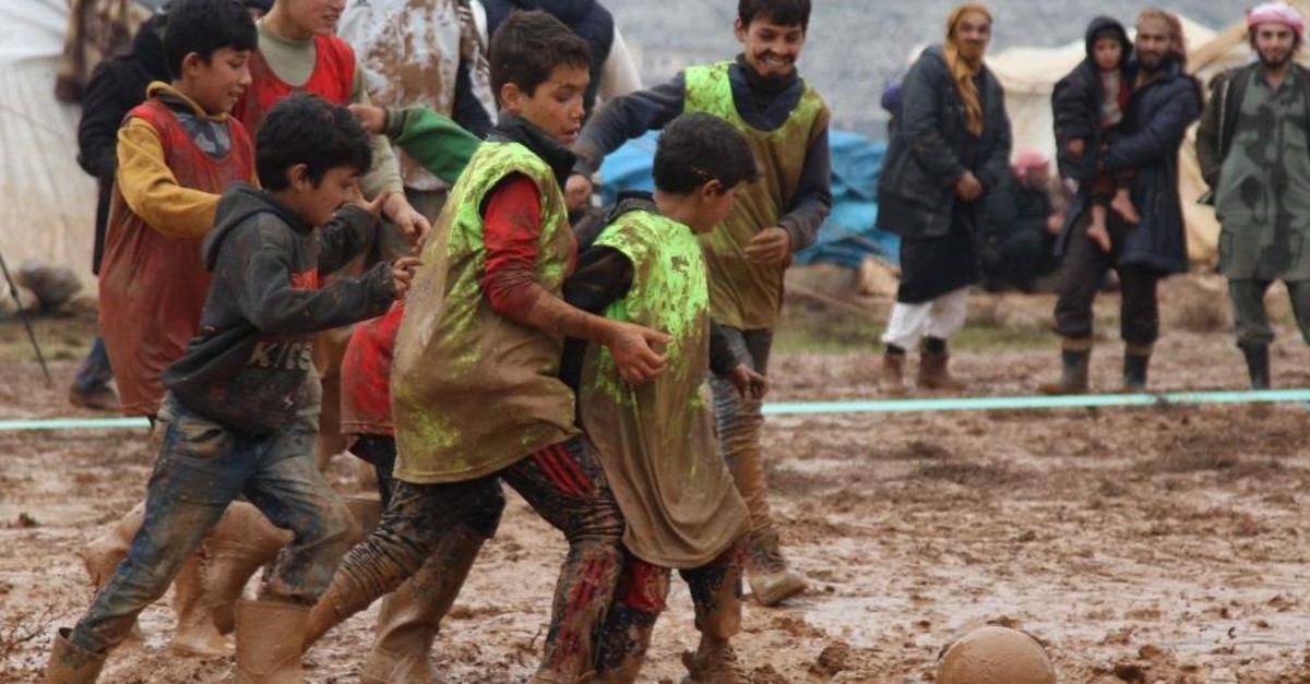Syrians play a game of football organized by local activists in a muddy field in a camp for the internally displaced west of the town of Sarmada in Syria's northwestern Idlib province, Jan. 2, 2020. - The latest round of violence in Syria's nearly nine-year war saw regime forces upping their deadly bombardment of the northwestern province of Idlib, forcing in December alone, according to the United Nations, some 284,000 from their homes in the jihadist-run region of some 3 million people. (Photo by Abdulaziz KETAZ / AFP)