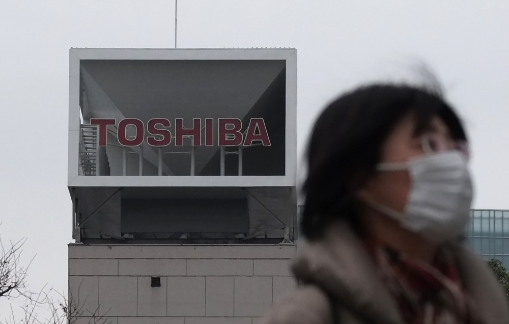 A woman walks in front of the logo of Japanese corportation Toshiba in Tokyo.