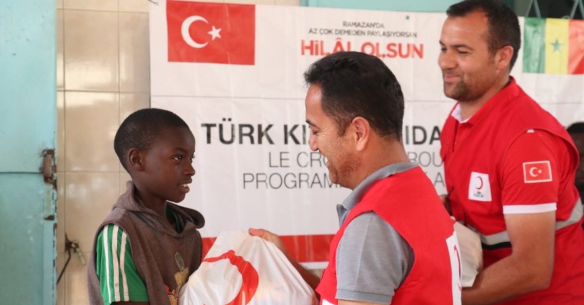 Red Crescent workers give a food package to a boy in Senegal's Dakar, May 31, 2019.