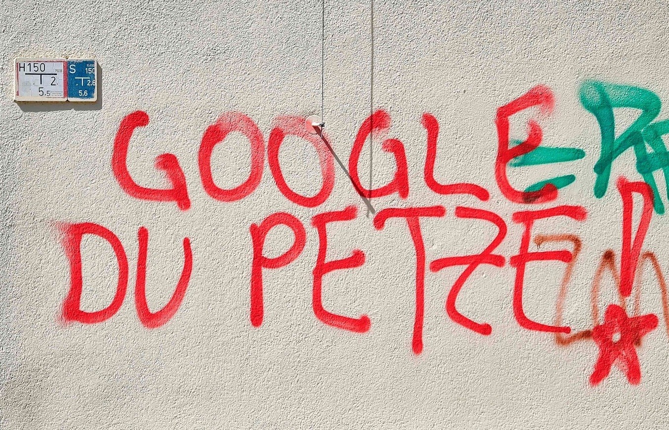 A woman sits next to graffiti reading u2018Google You Informer!u2019 in Berlinu2019s Kreuzberg district.