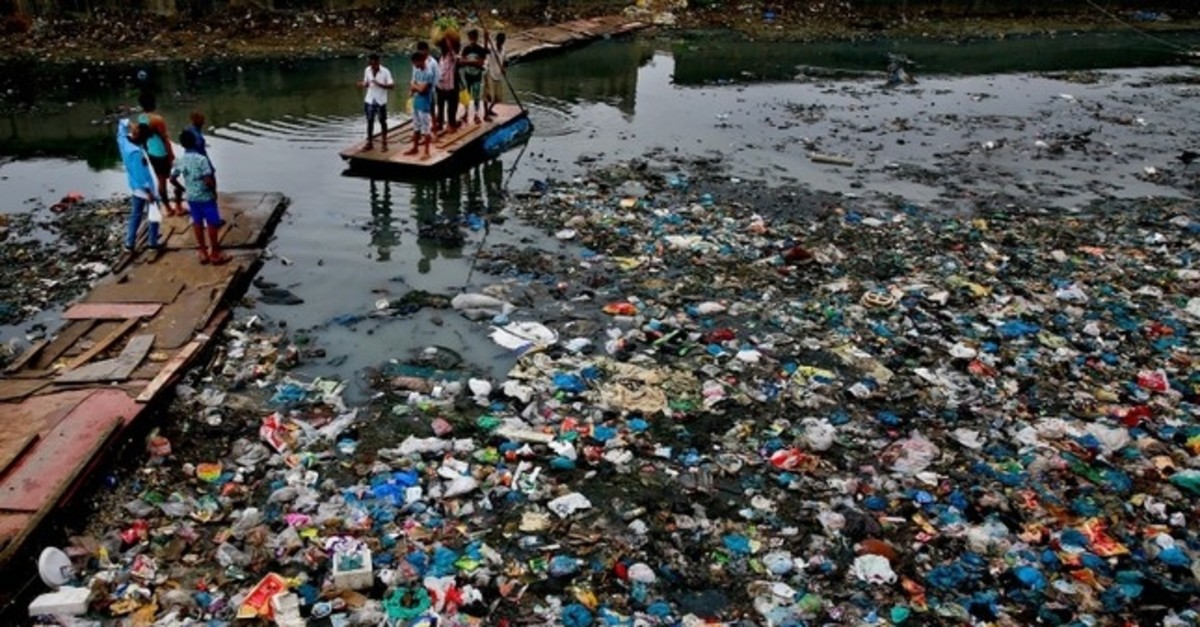 In this Sunday, Oct. 2, 2016 file photo, a man guides a raft through a polluted canal littered with plastic bags and other garbage in Mumbai, India. (AP Photo)