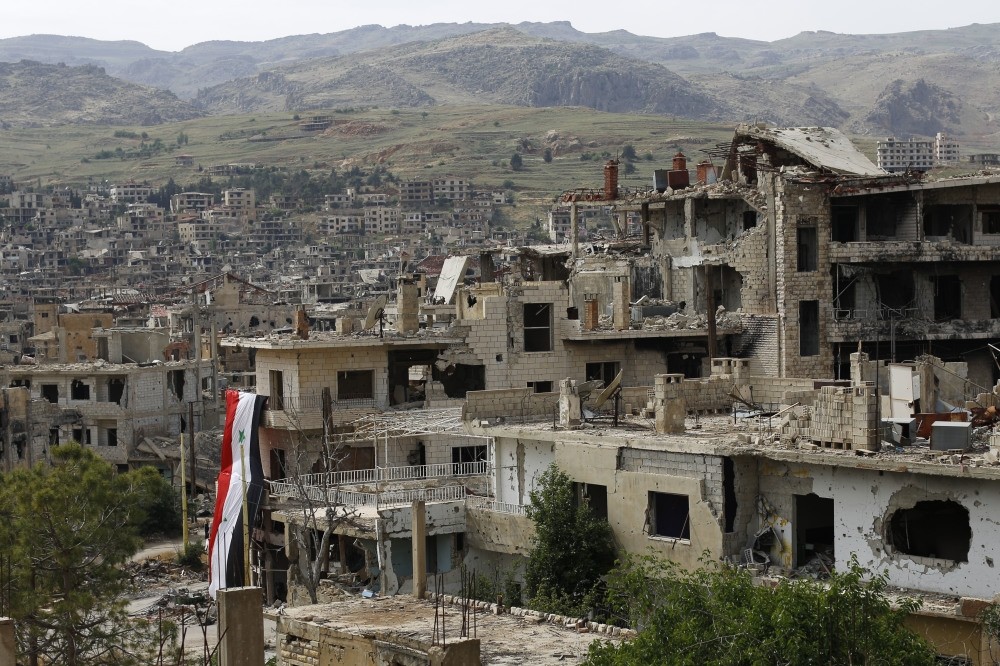 A Syrian national flag hangs off a damaged building at the mountain resort town of Zabadani in the Damascus countryside, Syria, May 18.
