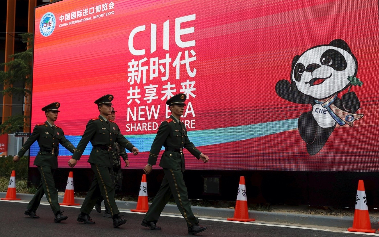 Paramilitary policemen march past a billboard for the China International Import Expo on the eve of its opening in Shanghai, Nov. 4.