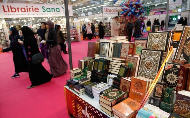 Visitors walking past a bookseller displaying copies of the Quran during the 32nd Annual Meeting of France's Muslims, at Le Bourget Exhibition center, north of Paris, April 3, 2015.