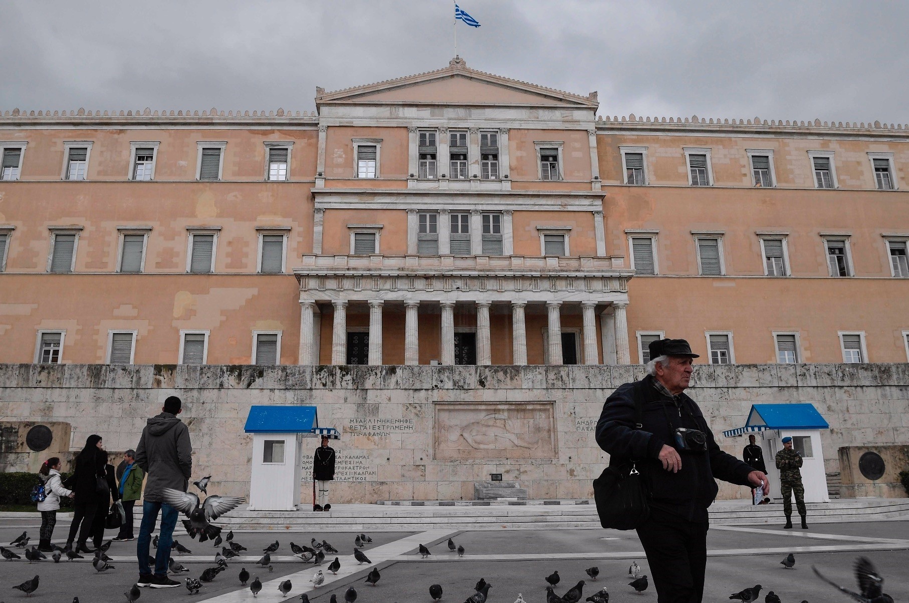 People walk in front of the Greek Parliament, central Athens, Feb. 8, 2019.