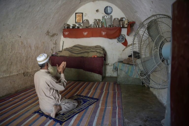 Pakistani villager Faqeer Gul praying in his cave room.