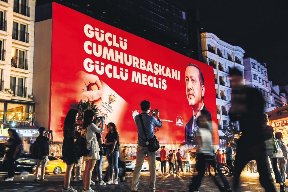 Tourists take pictures of a banner with a portrait of President Recep Tayyip Erdou011fan, Taksim Square, Istanbul, June 19.