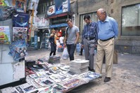 People reading the headlines of Iranian newspapers at a newsstand, in Tajrish Square, Tehran, July 7, 2015.