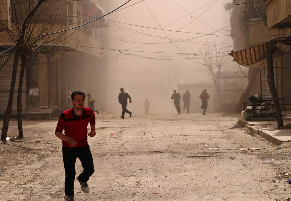 Syrian civilians running for cover as smoke billows following an airstrike on Ain Tarma, in the eastern Ghouta area, a moderate opposition-stronghold, east of the capital Damascus on March 27. 
