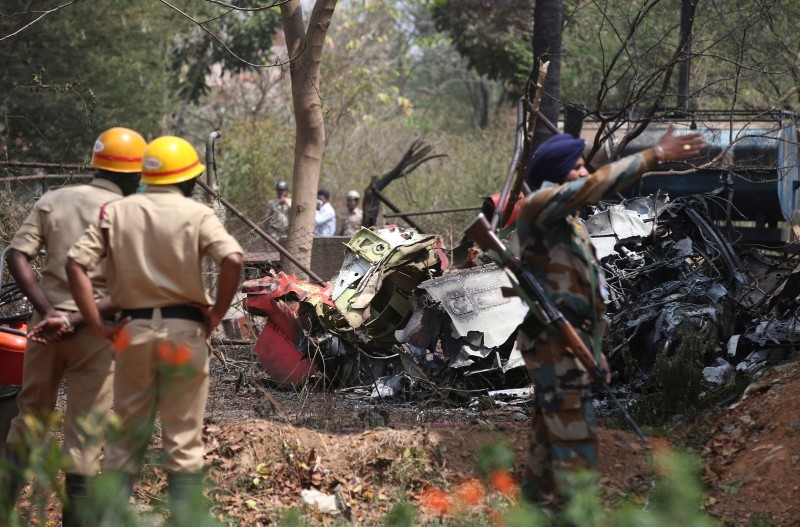 Firefighters and security officers secure the area by the wreckage after two Indian Air Force aircrafts collided midair while rehearsing for Aero India 2019 near Yelahanka air base in Bangalore, India, Feb. 19, 2019. (AP Photo)