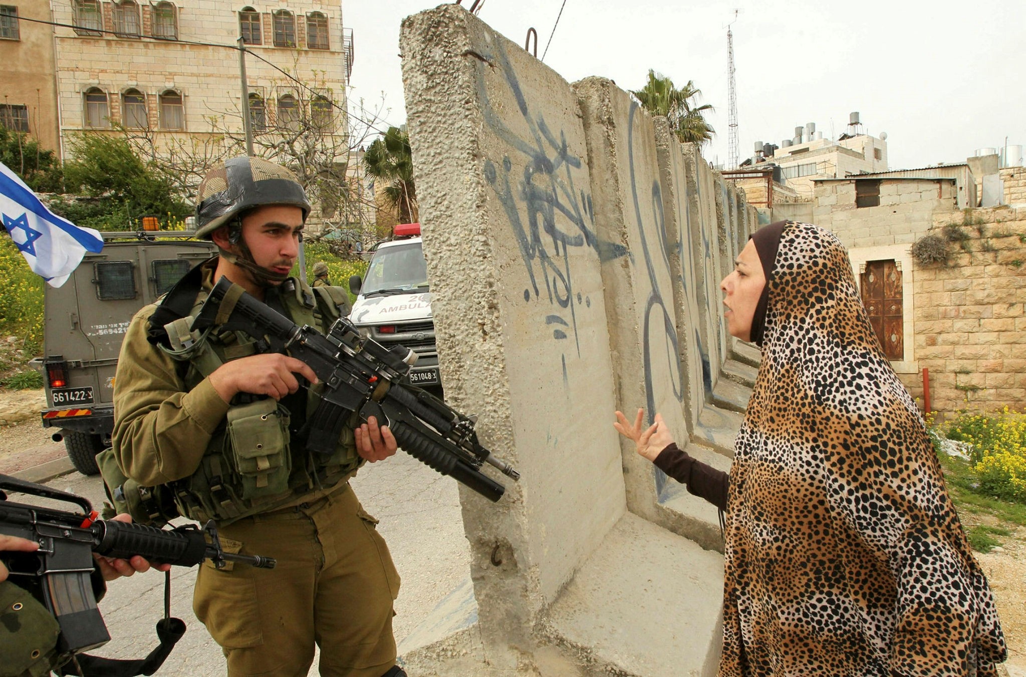 A Palestinian woman speaks with an Israeli soldier at the entrance of the heavily guarded Jewish settler enclave in the city center of the West Bank on March 24.