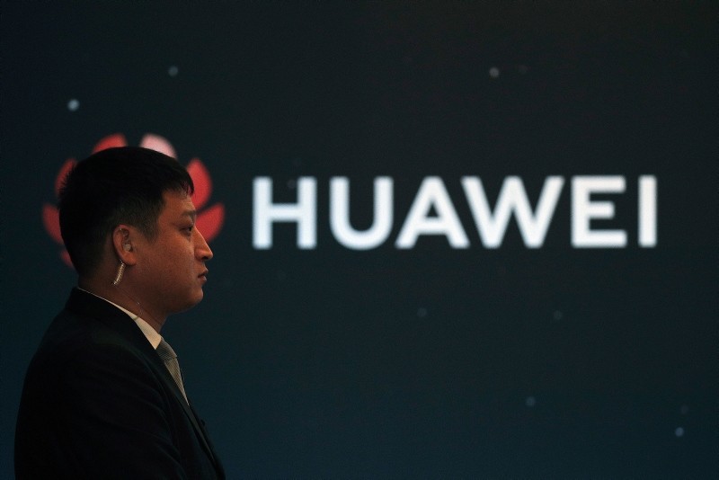 In this Jan. 9, 2019, photo, a security guard stands near the Huawei company logo during a new product launching event in Beijing. (AP Photo)