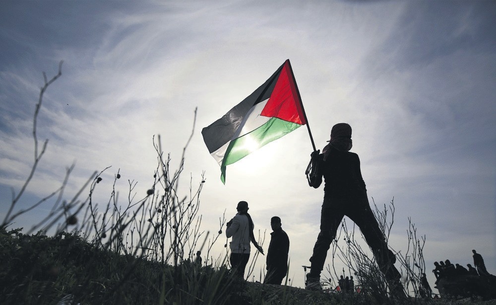 A Palestinian protester holds a Palestinian flag during clashes after Israeli troops attacked protesters near the border between Israel and the Gaza Strip, March 2. 