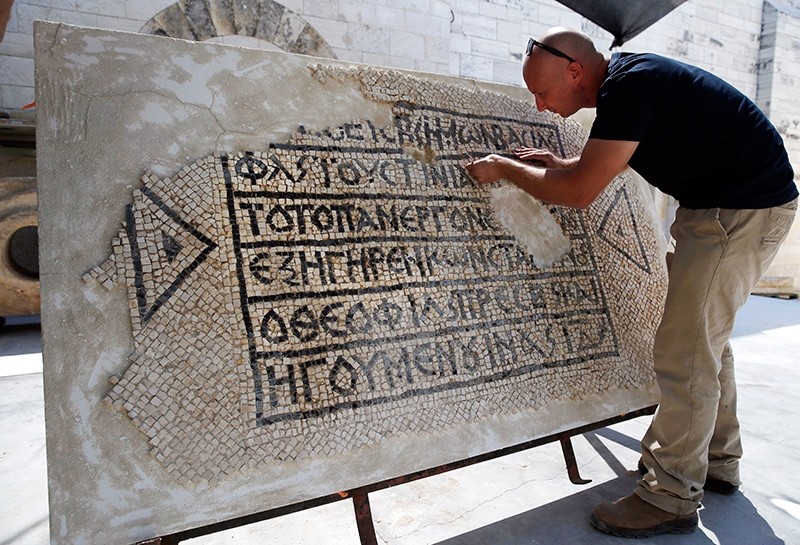 An archaeologist works on part of a 1,500-year-old mosaic floor bearing the names of Byzantine Emperor Justinian, at the Rockefeller Museum in Jerusalem, on August 23, 2017 (AFP Photo)