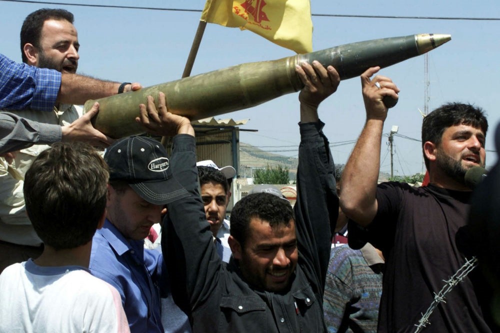 Lebanese demonstrations hold up an Israeli tank shell left behind by withdrawing Israeli troops along the Israel-Lebanon border near Metulla.
