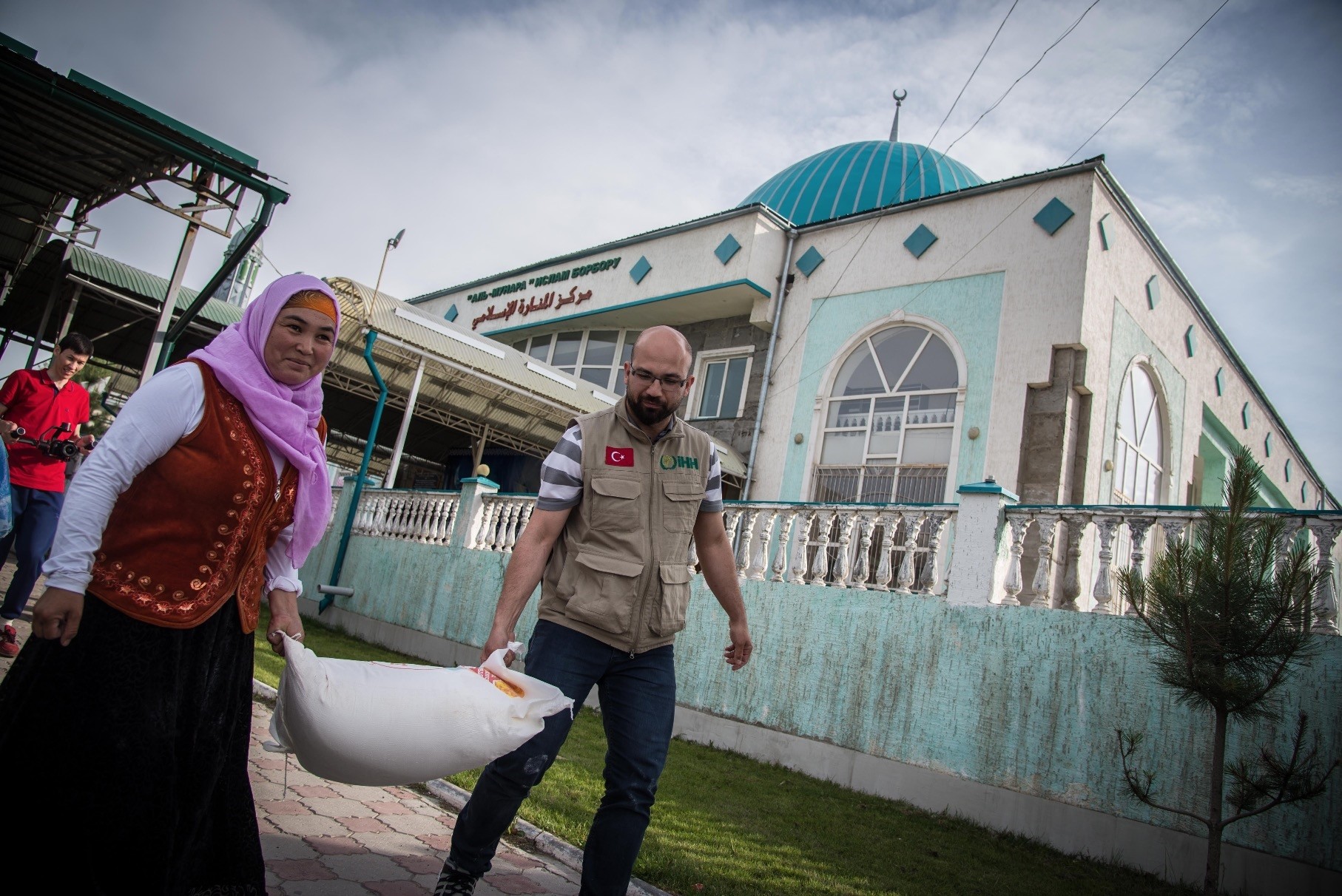 A Turkish charity worker helps a Kyrgyz woman carry her aid package.